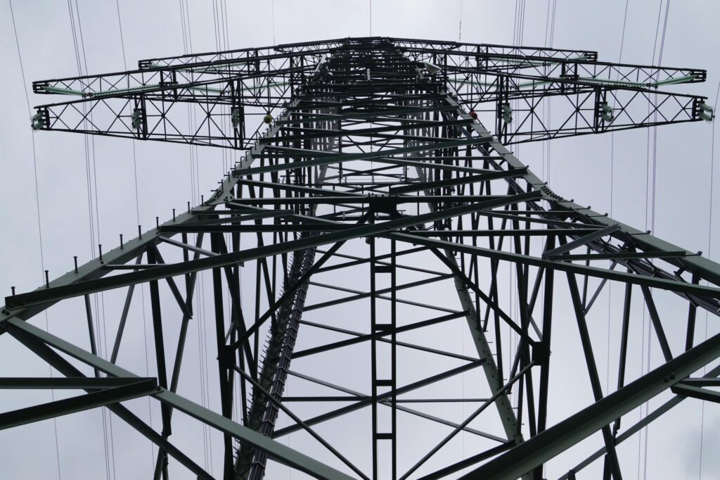 Close-up low angle view of a metal electricity pylon against a cloudy sky.